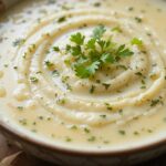 Bowls of creamy potato soup with herbs and bread.