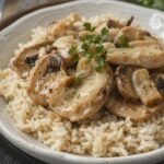 Serving a comforting plate of cream of mushroom chicken with rice, garnished with fresh herbs.